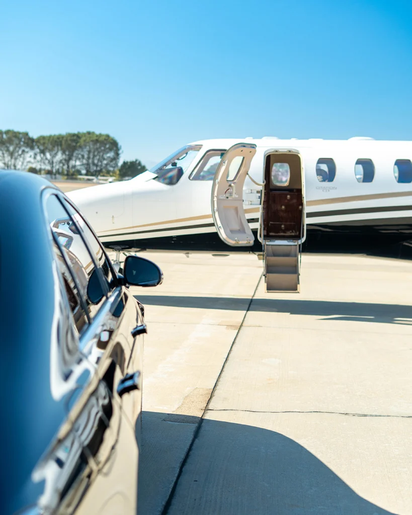 Private car arriving beside a private aircraft with its door open